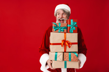 Image of joyful gray-haired old Santa Claus man holding gift boxes