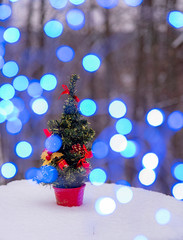 Artificial Christmas tree on a stump in the winter forest