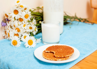 Fototapeta na wymiar Simply stylish wooden kitchen with bottle of milk and glass on table, summer flowers camomile, healthy foog moring concept close up