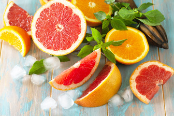 Ingredients for making a refreshing drink. Grapefruit, orange, ice and basil on a wooden table.