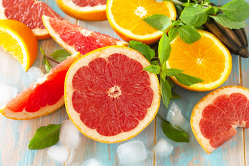 Ingredients for cooking a refreshing drink. Grapefruit, orange, ice and basil on a wooden table.