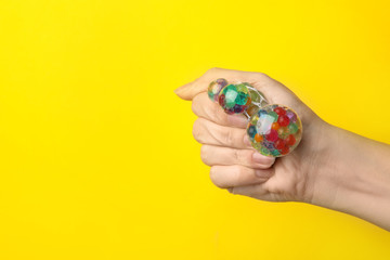Woman squeezing colorful slime on yellow background, closeup. Antistress toy