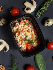 Culinary dishes made from natural products in a plastic bowl on the background with ingredients for cooking. Healthy food delivery concept. Top view.