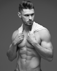Portrait of a young man with a beard. A man in a t-shirt on a gray background. black and white photo. Studio portrait in a fashionable style. Fashion and advertising