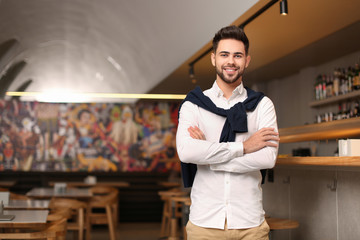 Young male business owner near counter in his cafe. Space for text