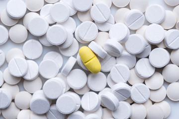 Pile of white pills and around a yellow one. The concept of different, alternative or placebo treatment - obrazy, fototapety, plakaty