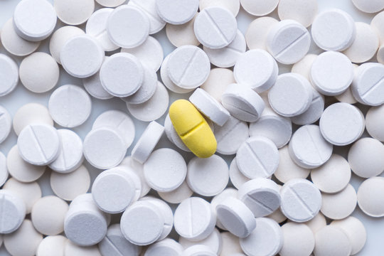 Pile Of White Pills And Around A Yellow One. The Concept Of Different, Alternative Or Placebo Treatment