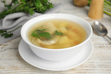 Delicious fish soup in bowl on white wooden table