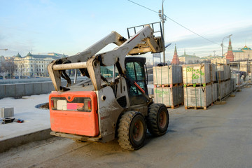 Repair of the sidewalk in a large city, tractor