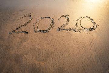 Happy New Year 2020 text on beautiful the sea beach with wave early morning sunrise over the horizon background.During Christmas and New Year.