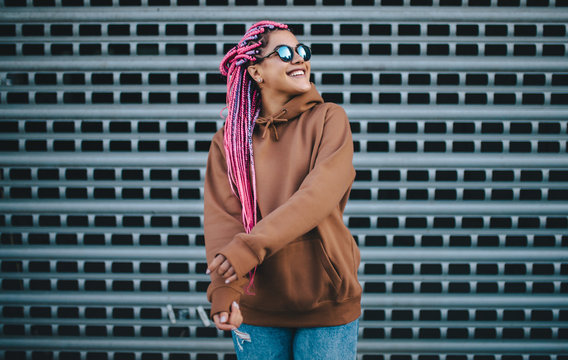 City portrait of handsome hipster girl with colored afro braids wearing brown blank hoodie or hoody with space for your logo or design. Mockup for print