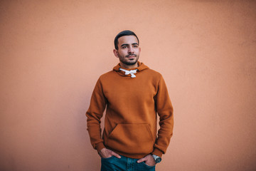 City portrait of handsome hipster guy with beard wearing brown blank hoodie or hoody with space for your logo or design. Mockup for print