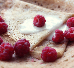 pancake with cream and raspberries on the table