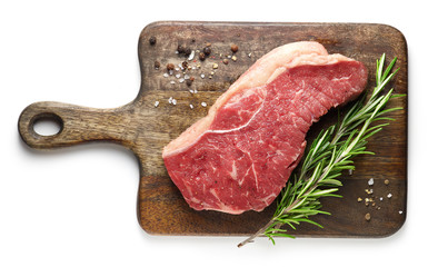 fresh raw beef steak on wooden cutting board with spices and rosemary isolated on white background