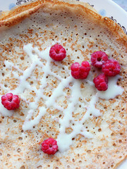 pancake with cream and raspberries on the table