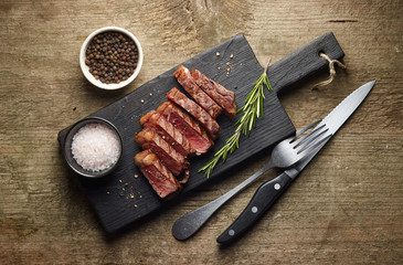 Grilled sliced beef steak on wooden board top view
