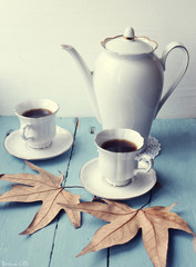 cup of coffee with teapot and leaf on the table