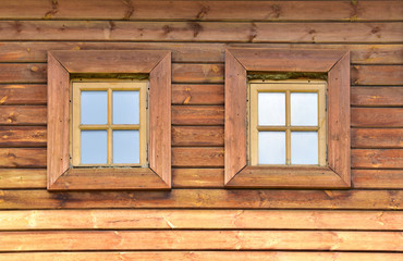 Two small wooden square windows in a plank wall