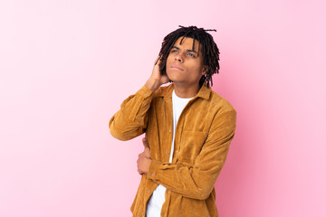 Young African American man with corduroy jacket over isolated pink background having doubts