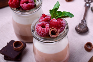 Three chocolate mousse dessert in a glass jar topped with frozen raspberries and mint