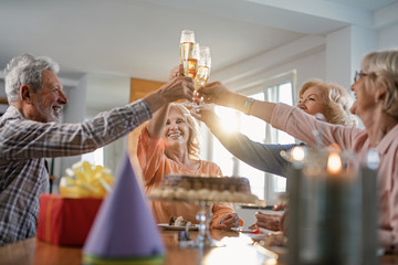 Below view of happy senior people toasting with champagne on birthday party.