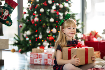 Young girl sitting on the floor holding christmas gift