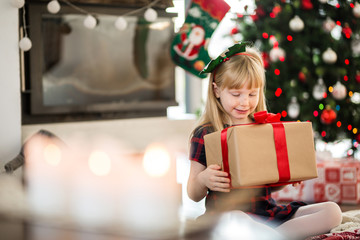 Young happy girl sitting on the floor with christmas present