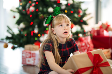 Young girl sitting on the floor holding present thinking