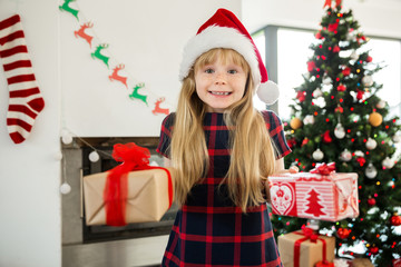 Young happy girl in santa hat holding presents