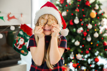 Young happy girl covering her eyes with gingerbreads