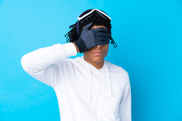 Fototapeta na wymiar Young African American man with snowboarding glasses covering eyes by hands