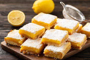 Homemade lemon bars with shortbread crust, on wooden background. 