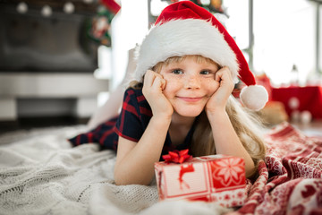 Young happy girl in santa hat lying on floor