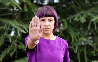Angry woman with in purple showing the hand palm saying STOP