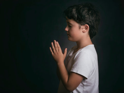 child with hands clasped together praying