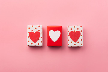 Valentines day, birhtday, wedding or other holiday composition. Handmade wrapped gift boxes, red hearts on pink background. Copy space for text. Flat lay