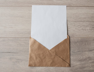 Blank paper envelopes on light wood table background.