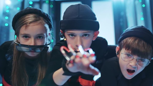 Teen special agent using robotic smart hand exoskeleton hacking a server computer with friends. Skillfull young spy kids breaking into secure data center on secret mission.