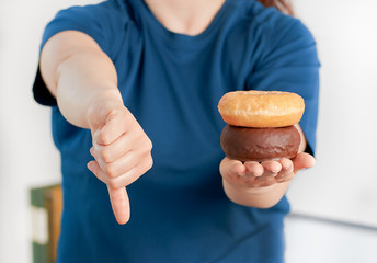 woman hand holding donuts with thumb down