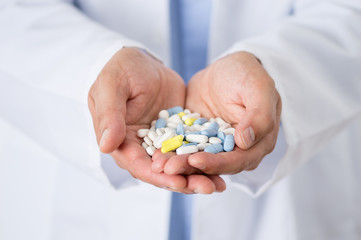 Closeup shot of an unidentifiable male doctor holding a variety of pills in her hands