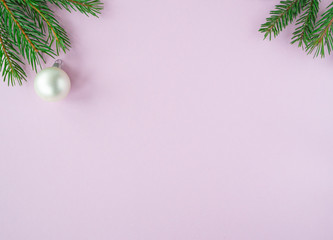 Christmas New year flat lay with xmas tree or branches, and ball on pink background. Greeting card, top view, copy space. 