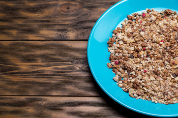 Muesli flakes in blue plate on wooden background - copy space
