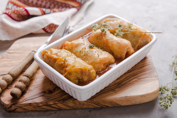 Meat in cabbage rolls in a white plate  with  sauce on stone  background.  Asian cuisine top view. Russian food