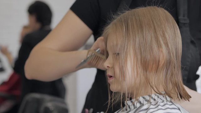Little girl in a beauty salon. The hairdresser makes a fashionable haircut to the child.