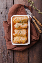 Meat in cabbage rolls in a white plate  with  sauce on wooden background.  Asian cuisine top view. Russian food