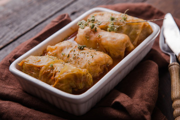 Meat in cabbage rolls in a white plate  with  sauce on wooden background.  Asian cuisine top view. Russian food