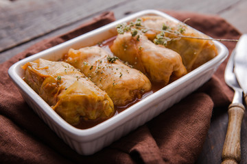 Meat in cabbage rolls in a white plate  with  sauce on wooden background.  Asian cuisine top view. Russian food