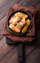Meat in cabbage rolls in a black pan with  sauce on wooden background.  Asian cuisine top view