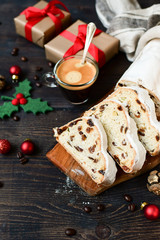 Christmas breakfast black coffee with sweet cake stollen. Traditional german and austrian festive dessert with dried berries, nuts and powdered sugar. top view, wooden background and gifts