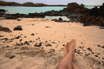 Pies en el la playa frente al mar sobre arena fina y rocas